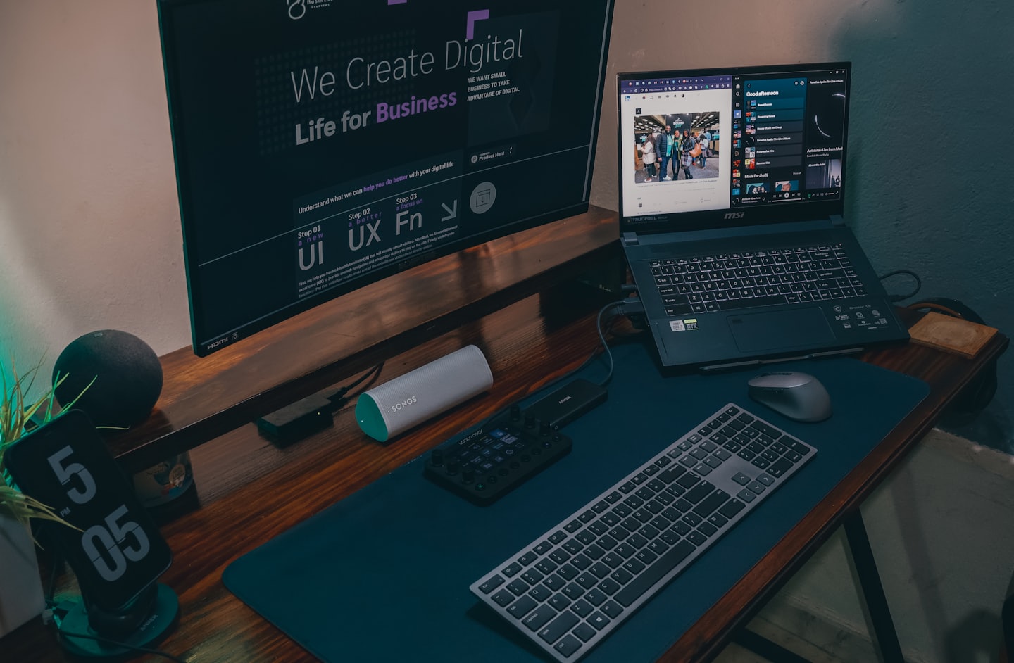 Laptop e monitor che mostrano contenuti digitali su una scrivania di legno.